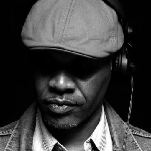 Black and white portrait of Dave Powell wearing a flat cap and headphones